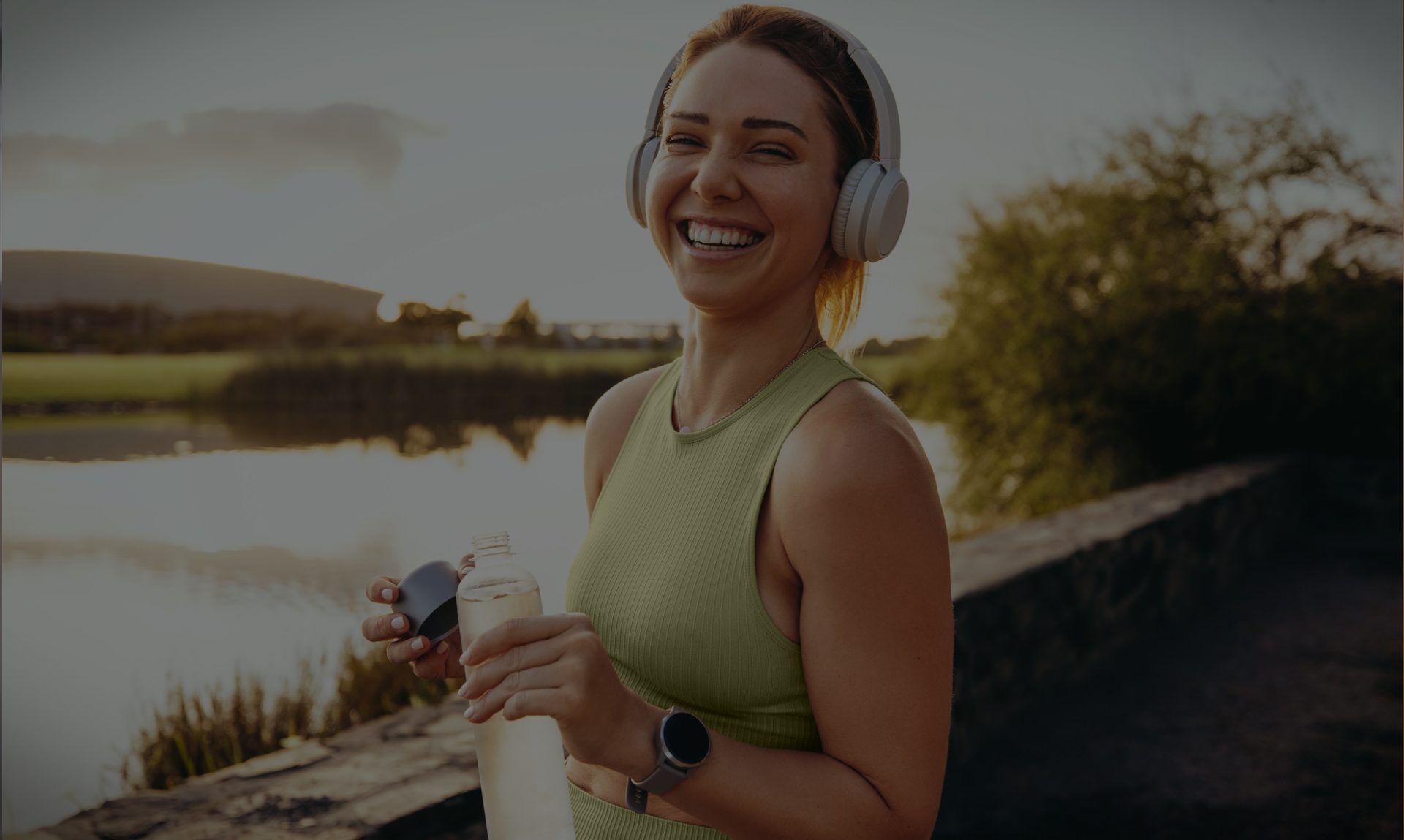 A woman smiling during an outdoor walk beside a lake at sunset